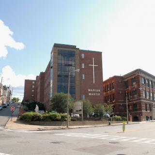 A modern hospital building featuring a prominent cross, set against a bright sky.