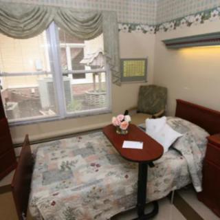 A cozy bedroom with a single bed, small table, and a window view.