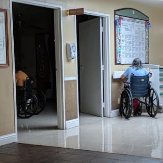A view of a care facility with individuals in wheelchairs, showcasing an environment focused on accessibility and assistance.