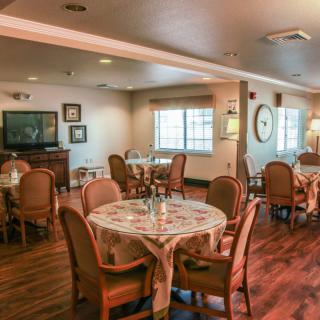 A cozy dining area with multiple tables and chairs, featuring a warm decor and wooden flooring.