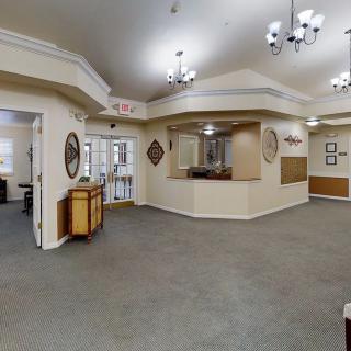 A spacious and well-lit reception area with chandeliers, carpeted flooring, and decorative elements.