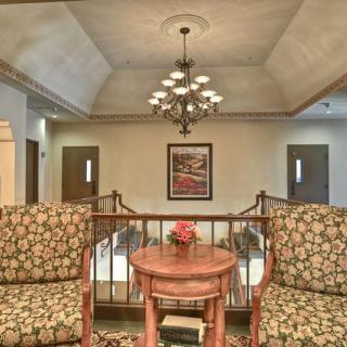 A cozy interior seating area with patterned chairs, a small table, and a chandelier overhead.