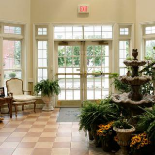 A well-decorated lobby featuring a central fountain, surrounded by lush plants and seating areas.