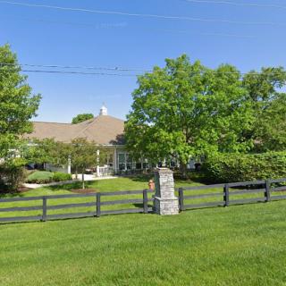 A suburban house with a large lawn and surrounding trees.
