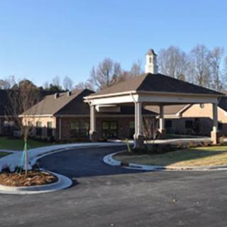 A building with a covered entrance and landscaped driveway.