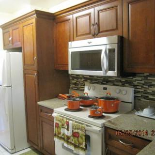 A modern kitchen with wooden cabinets and a variety of appliances, including a microwave and stovetop with orange pots.
