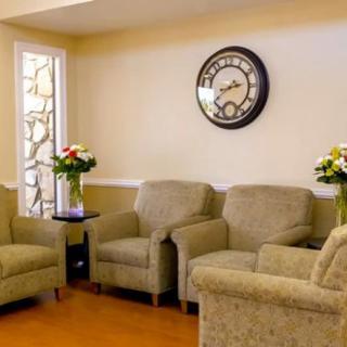 A cozy living room with comfortable chairs and decorative elements like a wall clock and flower vases.