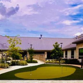 A building with a putting green in the courtyard under a cloudy sky.