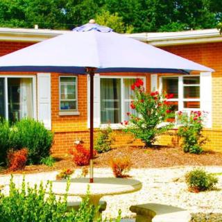 A patio area with a large umbrella and outdoor furniture surrounded by a landscaped garden.
