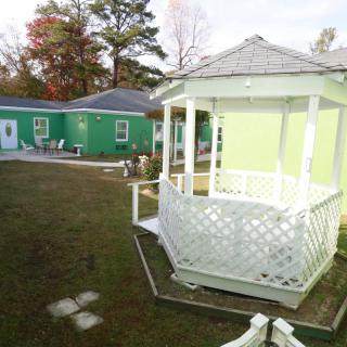 A charming outdoor scene featuring a white gazebo and a green building, surrounded by a well-kept yard.
