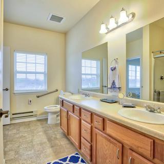A spacious bathroom featuring double sinks, wooden cabinets, and a large mirror.