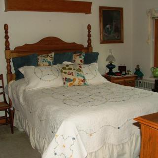 A cozy bedroom with a wooden bed frame, adorned with decorative pillows and a quilt.