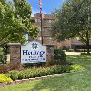 Entrance sign for Heritage Place Retirement Community surrounded by trees and greenery.