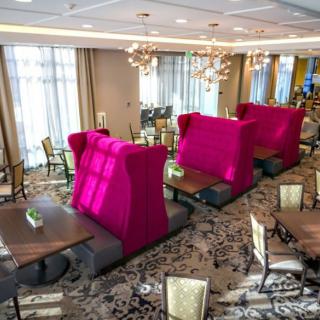 A modern restaurant interior with vibrant pink seating and elegant chandeliers.