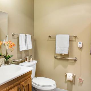 A clean and organized bathroom featuring a toilet, sink, mirror, and neatly hung towels.