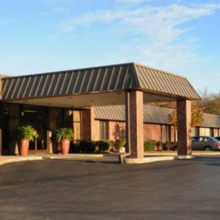 Entrance of a commercial building with a parking area in the foreground.