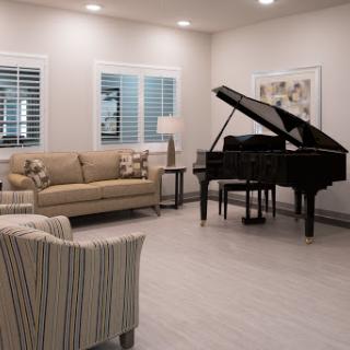 A cozy living room featuring a grand piano, stylish seating, and warm lighting.