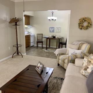 A cozy living room with an open space leading into a small kitchen area.