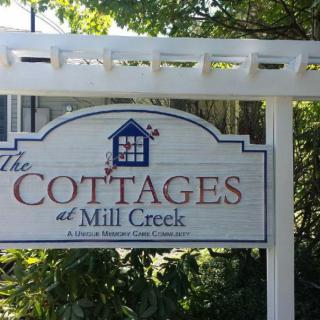 Sign for The Cottages at Mill Creek surrounded by greenery.