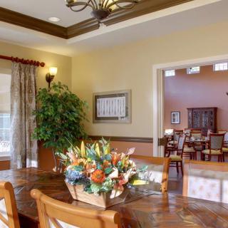 A well-decorated dining room featuring a wooden table, chairs, floral arrangement, and elegant lighting.