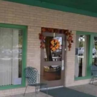 An inviting entrance decorated with autumn leaves, featuring green chairs and glass windows.