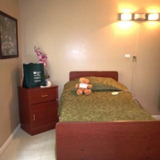 A cozy bedroom with a single bed, nightstand, and a teddy bear.