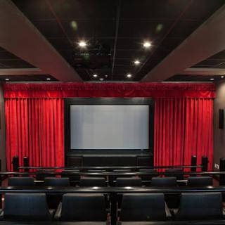 A cozy home theater setup featuring a large screen and plush seating with elegant red curtains.