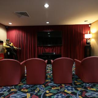 A cozy home theater setup with red chairs and a vibrant carpet.