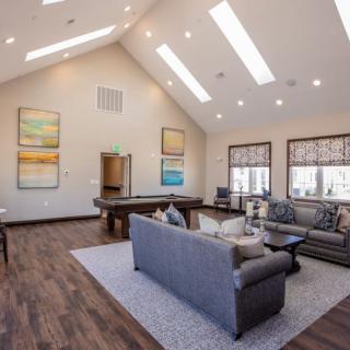 A spacious, modern living room with high ceilings and ample natural light from skylights, featuring comfortable seating and elegant decor.