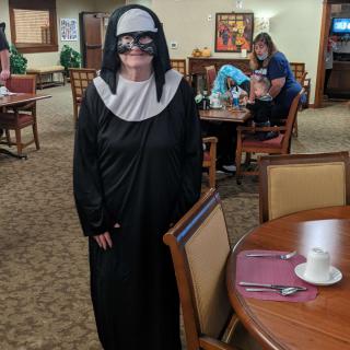 A person dressed in a nun costume stands in a restaurant setting.