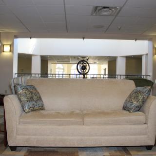 A beige sofa with patterned pillows in a living room setting.