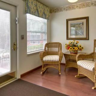 Cozy waiting area with wicker chairs and floral decor by a window.