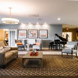 A cozy and elegantly designed living room featuring a comfortable seating arrangement, a grand piano, and stylish decor.