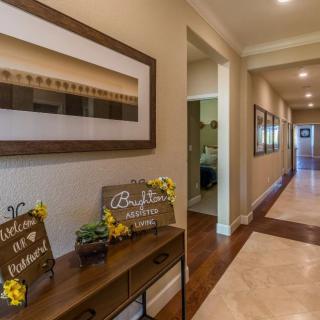 A warmly decorated hallway with artwork, wooden flooring, and welcoming signs.