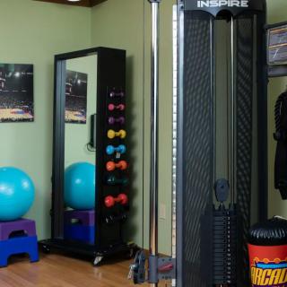 A well-equipped home gym with various exercise equipment including weights and a stability ball.