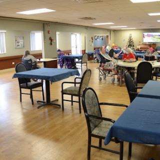 A spacious dining area in a community center, featuring tables with blue tablecloths and ample seating.