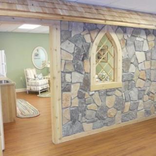 A cozy interior space featuring a stone wall with a decorative window and wooden flooring.