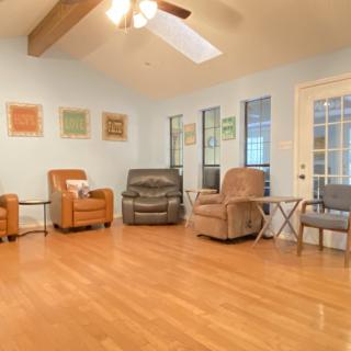 A cozy living room with multiple armchairs and a ceiling fan.