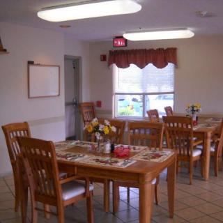 A cozy dining room with wooden tables and chairs, decorated with flowers and placemats.