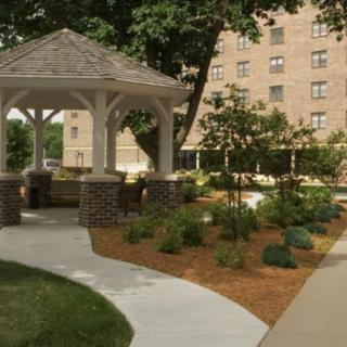 A serene garden with a gazebo and landscaped pathways near a building.