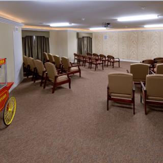 An indoor conference room with neatly arranged chairs and a popcorn cart in the corner.