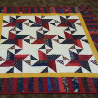 A beautifully crafted quilt featuring a geometric star pattern in red, white, blue, and yellow colors.