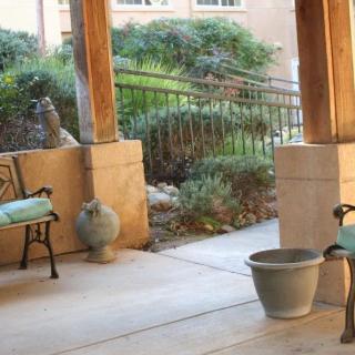 A serene porch area with benches and decorative planters, overlooking a lush garden.