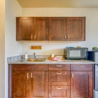 A compact kitchen area featuring wooden cabinets, a countertop with a sink, and a microwave.