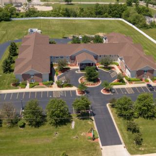 Aerial view of a building surrounded by greenery and parking spaces.