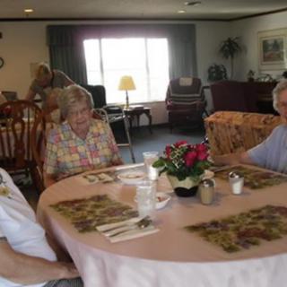 A group of elderly individuals sitting at a table in a communal dining area.