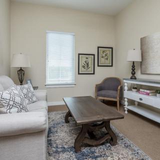 A cozy living room with a neutral color palette, featuring a sofa, coffee table, and decorative artwork.