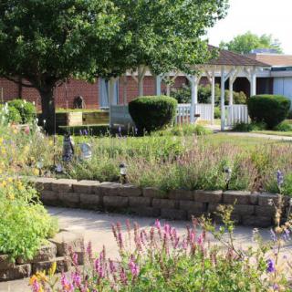 A serene garden with a gazebo surrounded by lush greenery and colorful flowers.