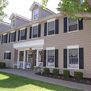 A charming residential building with a classic facade, featuring white shutters and a well-maintained lawn.
