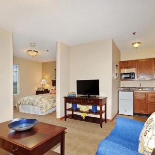 A cozy studio apartment featuring a combined living space with a kitchenette, small dining area, and sleeping area.